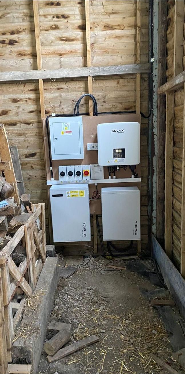 A SolaX inverter and batteries fitted on the wall of a timber barn