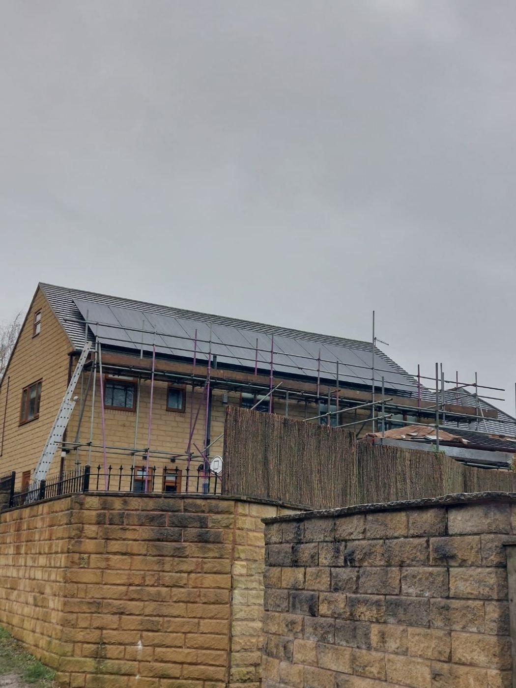 Stone house with scaffolding and black solar panels covering the roof